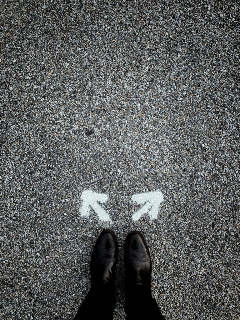 A person standing at a crossroads — Photo by Jon Tyson on Unsplash