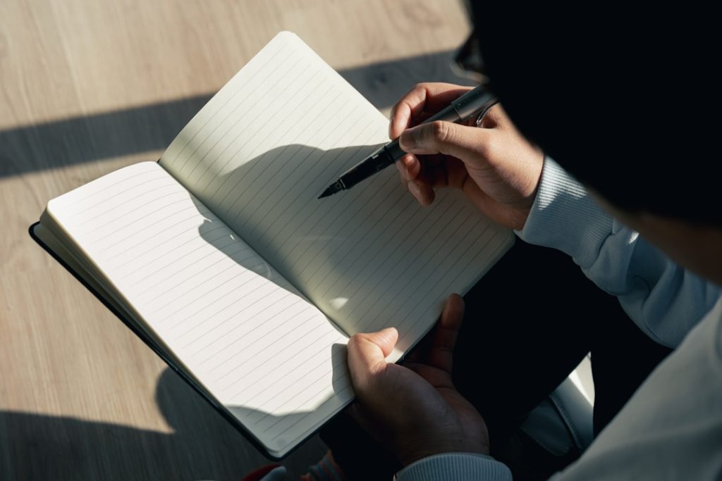 A person sitting down writing in a notebook